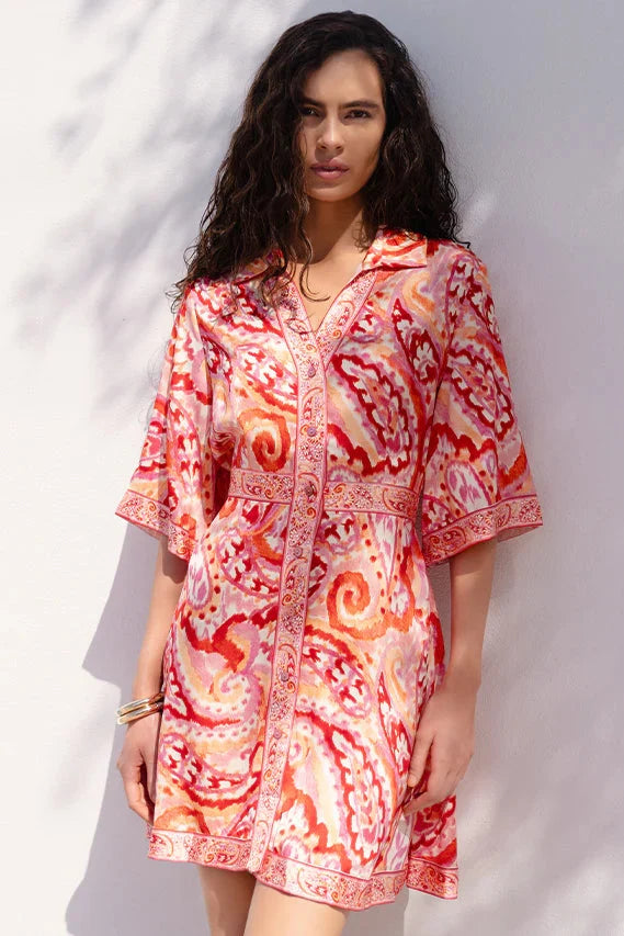 Woman wearing a red and orange patterned dress against a white background