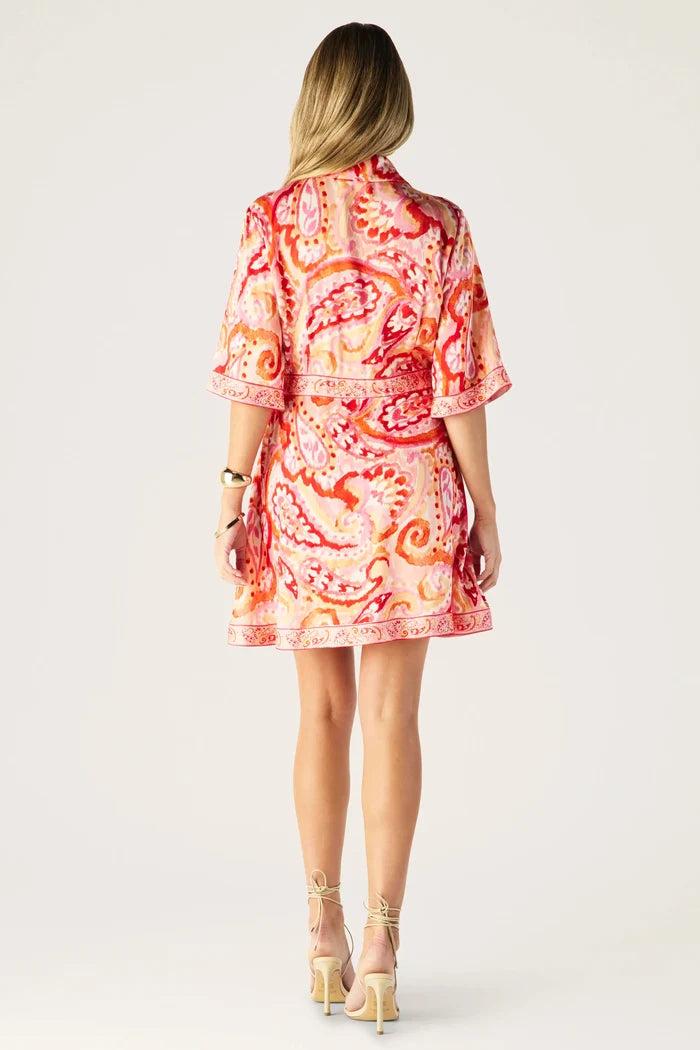 Woman wearing a red and orange patterned dress on a white background
