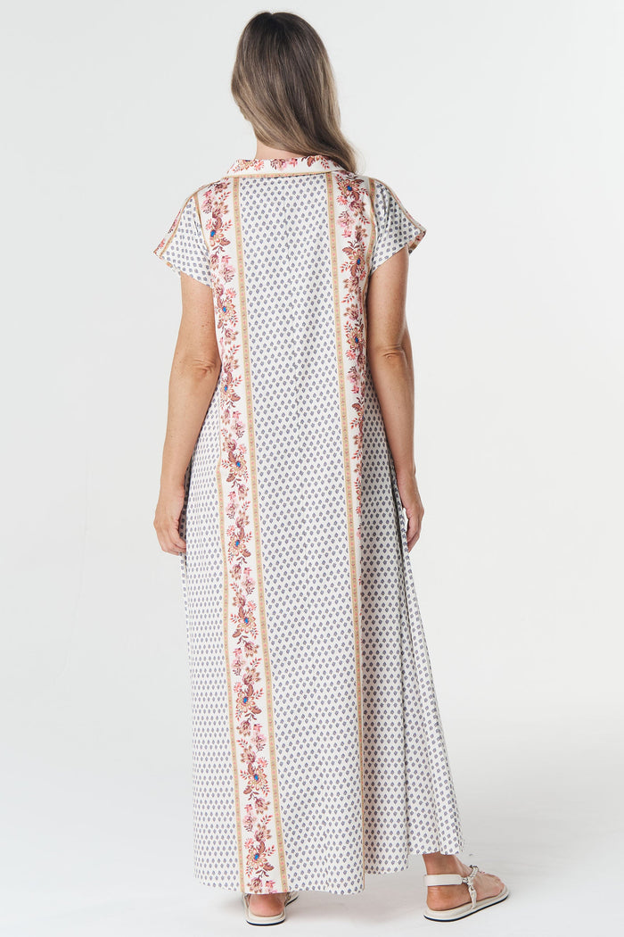 Woman wearing a long, patterned dress with a floral scarf on a white background