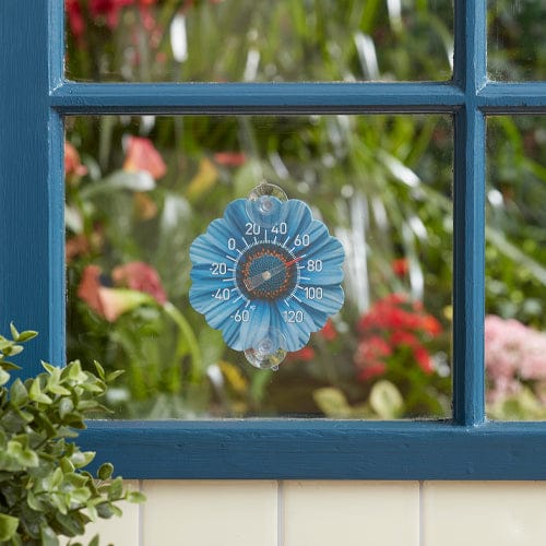 Blue daisy shaped silicone suction cup thermometer attached to a blue window.