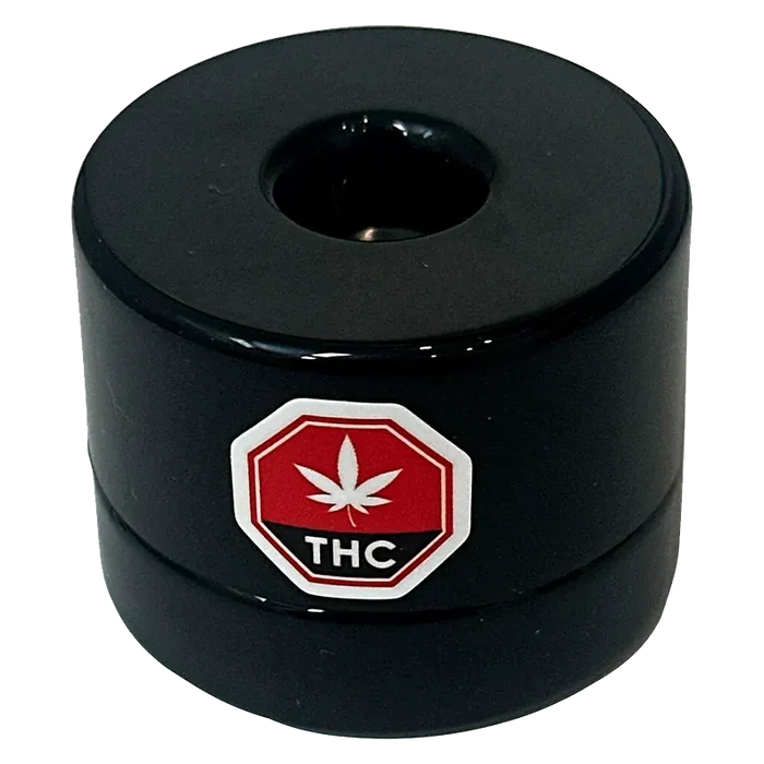 Top-down view of the black Single Source Live Rosin puck with a central depression and a red THC leaf octagon logo on its side