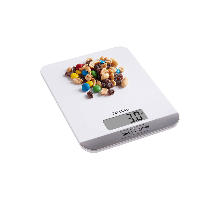 White digital kitchen scale with colorful candies and nuts on the weighing surface