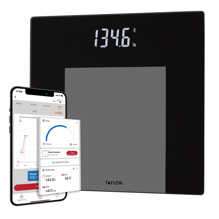 Person stands on a black weight tracking scale with weight shown on the display and a phone screen with metrics.