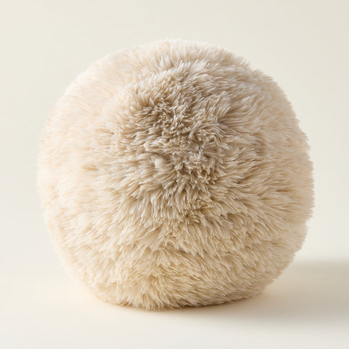 A plush, ball-shaped sphere accent pillow with a soft texture in a neutral color.