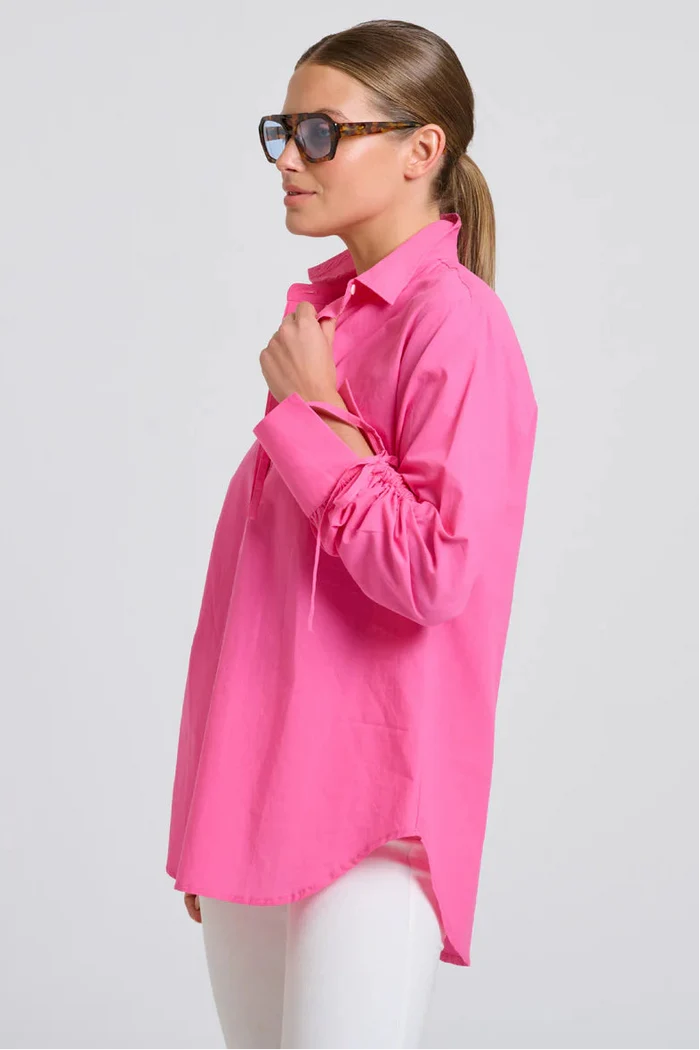 Woman wearing a bright pink shirt on a light gray background