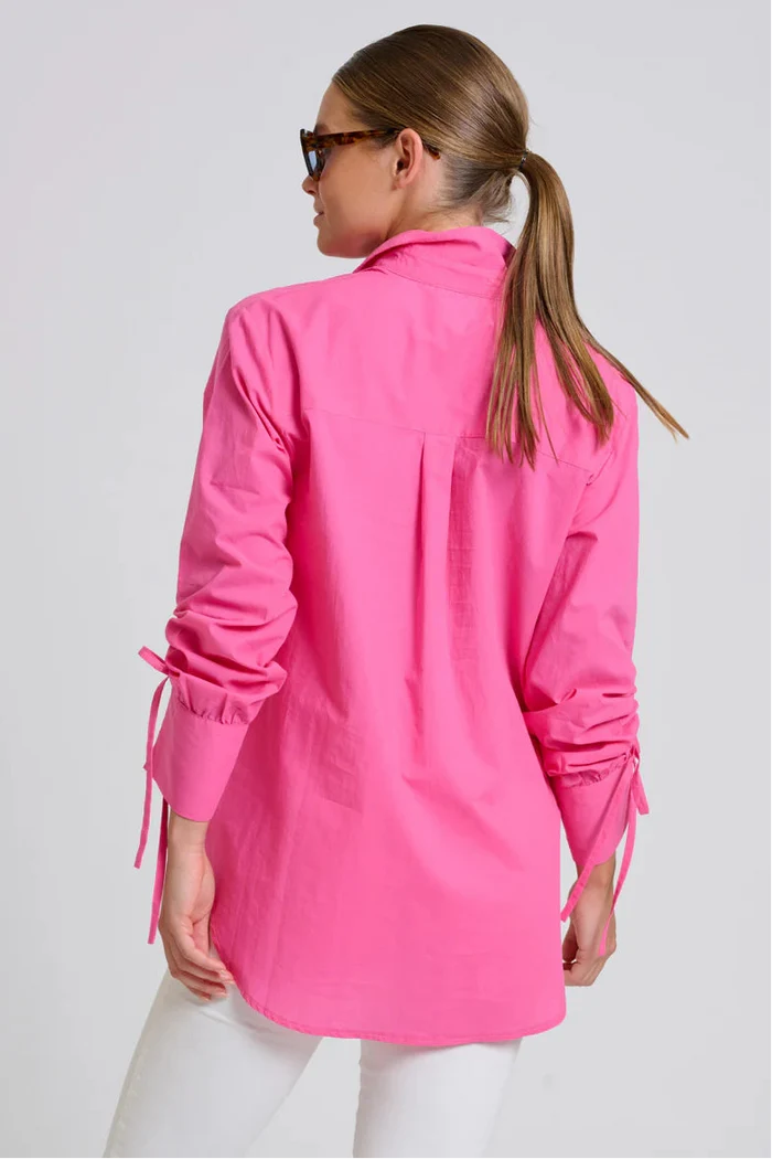 Person wearing a bright pink jacket with long sleeves on a plain background