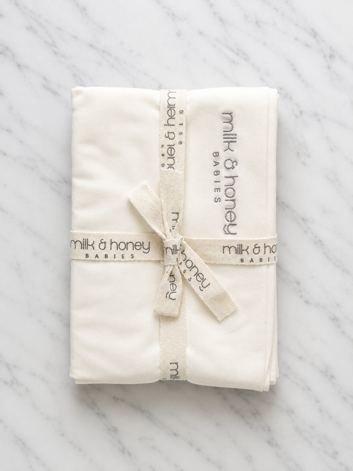 The Organic Swaddle folded and tied with milk and honey babies ribbon, undyed ivory organic cotton