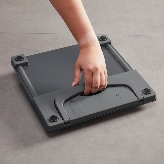 Forearm resting on the gray top of a portable scale with a neutral background.