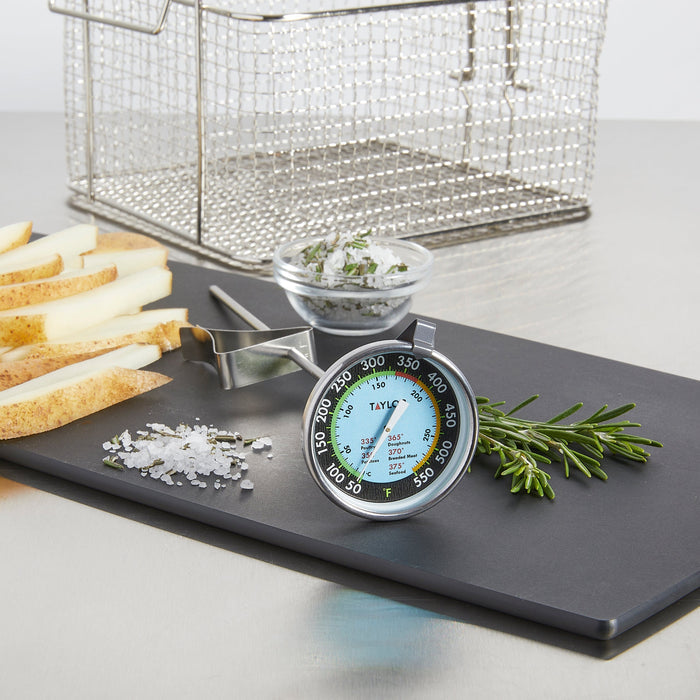 TruTemp Deep Fry Thermometer in foreground with a wire fryer basket and slices of bread on a cutting board nearby.