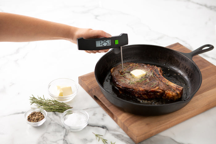 TruTemp Ultra-Fast Thermometer inserted into steak in a cast iron skillet on a wooden board
