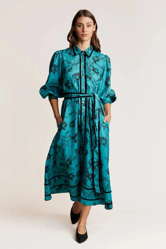 Woman wearing a teal dress with black patterns on a white background