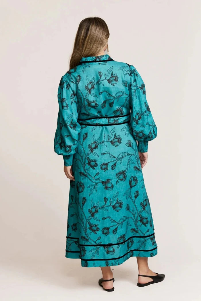 Woman wearing a teal floral dress with long sleeves on a white background