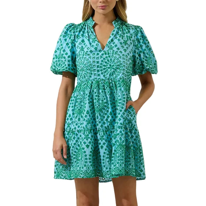 Woman wearing a green patterned dress against a plain background