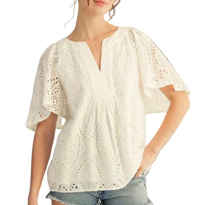 Woman wearing a white lace top with a plain background