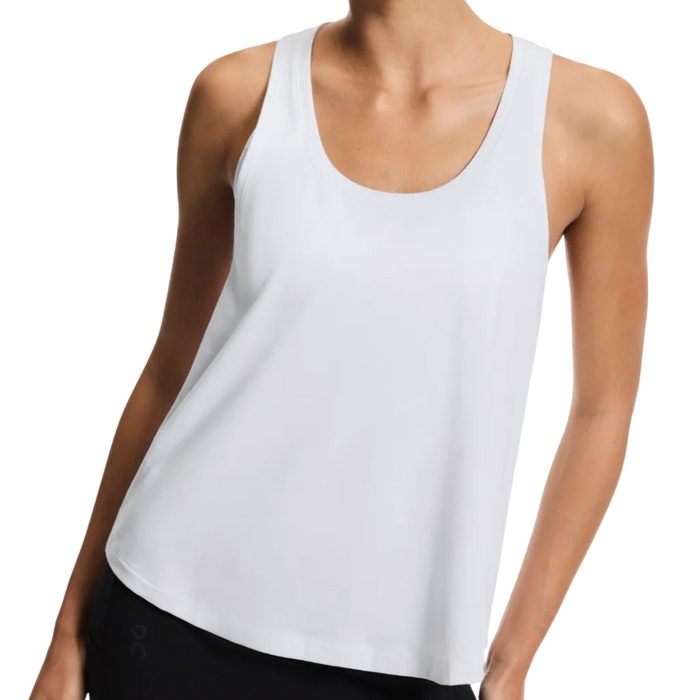 Woman wearing a white tank top on a plain background