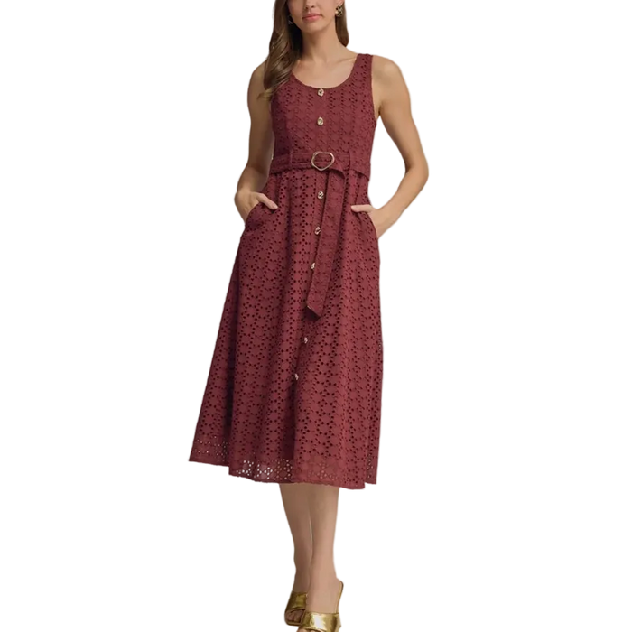 A woman modeling a sleeveless midi dress in a dusty rose red color with a matching waist belt and gold buckle. The dress features a textured geometric pattern and button details down the front.