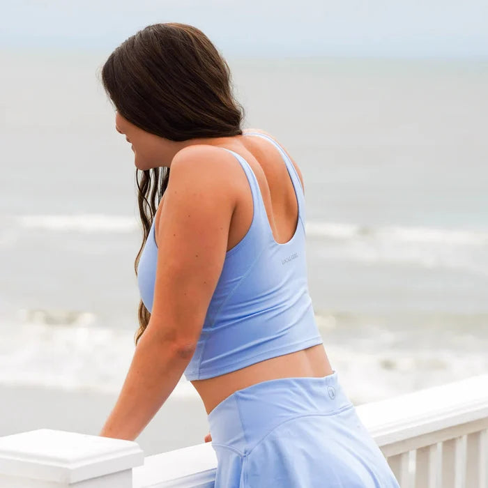 Woman in a light blue athletic outfit standing on a white railing.