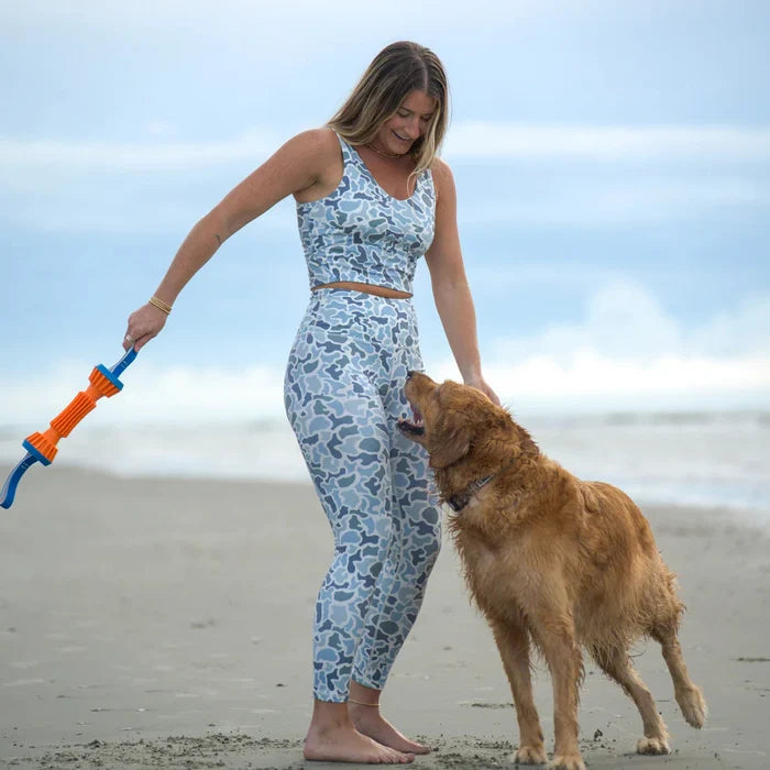 Woman playing with a dog on a beach using a toy