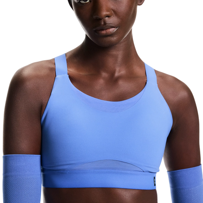 Person wearing a blue sports bra and arm sleeves on a white background
