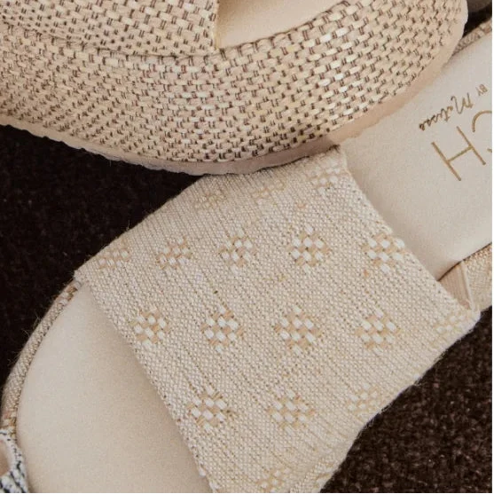 Close-up of beige high-heeled shoes with textured details on a white background